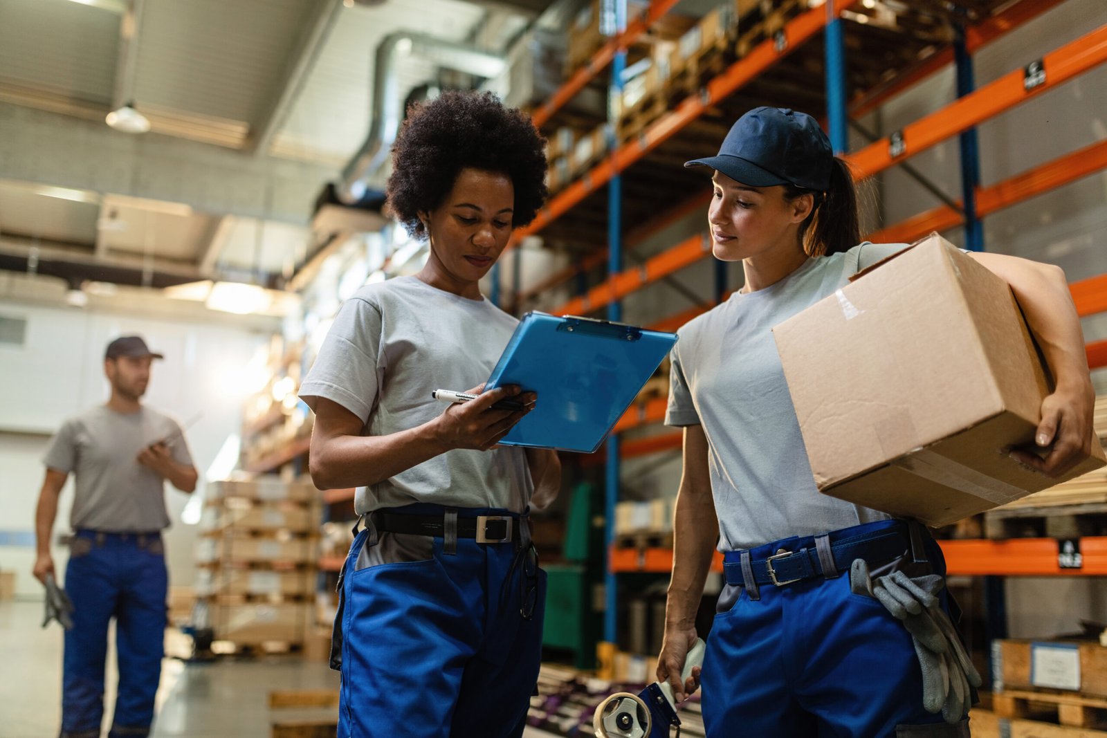 below view of female warehouse workers going through shipment list.
